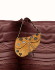 Brown leather saddle bag with decorative elements on a brown leather background